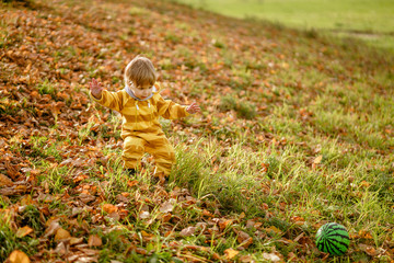 Concept: family, kids. Happy little child, baby boy laughing and playing with green ball in the autumn on the nature walk outdoors at park