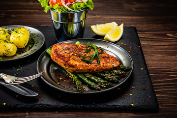 Grilled chicken fillet and vegetables on stone plate