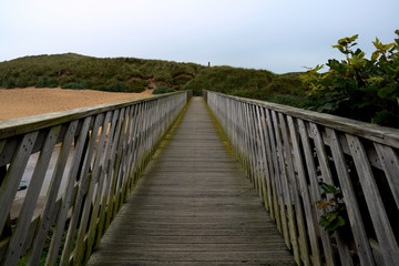 Obraz premium Wooden Footbridge Over a River Estuary to the Beach