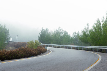 Ramp of a road with bending in a foggy day.