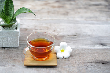Red tea in transparent glass with flower and plant pot on rustic wooden table