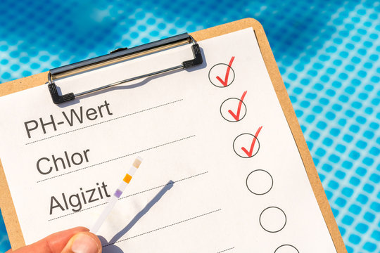 Prüfung der Wasserqualität eines Pools mit Hilfe eines Teststreifens für die Werte in deutscher Sprache für PH-Wert, Chlor und Algizit