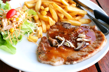 closeup pork chop steak with salad and frenchfried