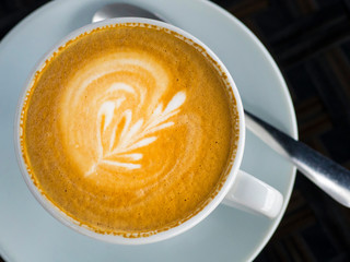 A cup of cappuccino coffee on a glass table in a cafe