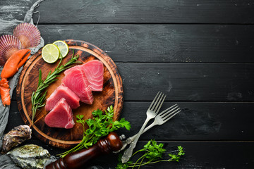 Raw tuna fillet. Seafood on a black stone background. Top view. Free copy space.