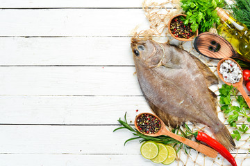 Raw flounder fish with spices. Seafood on a white wooden background. Top view. Free copy space.