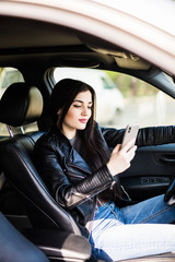 Young woman sending messages while driving her car