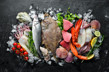 Fresh seafood and fish on black stone background. Flounder, lobster, squid, tuna, fish. Top view. Free copy space.