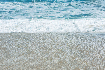 Sandy coast of the turquoise sea. Surging waves, sunny windy day. Space for text.