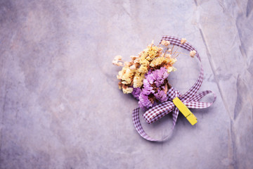 Dry flower bouquet with fabric ribbon on cement texture background, vintage purple tone style, celebrate and greeting card background idea