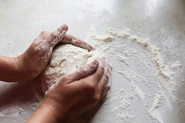 Unknown female hands making dough for pastry, having enough flour on white table, practising baking skills, spending her free time at kitchen, making shape of pastry. People and baking concept.