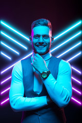 Young handsome model posing in a studio in a trendy neon light. Fashionable man in a stylish suit. Vibrant color. Bright colorful light effects. Disco style. Overlay. Gel filter. Supersaturated