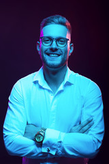 Young handsome model posing in a studio in a trendy neon light. Fashionable man in a stylish suit. Vibrant color. Bright colorful light effects. Disco style. Overlay. Gel filter. Supersaturated