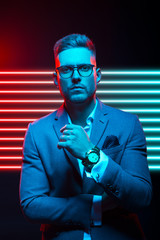 Young handsome model posing in a studio in a trendy neon light. Fashionable man in a stylish suit. Vibrant color. Bright colorful light effects. Disco style. Overlay. Gel filter. Supersaturated