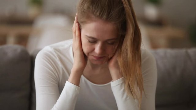 Anxious addicted young woman sitting alone on couch at home