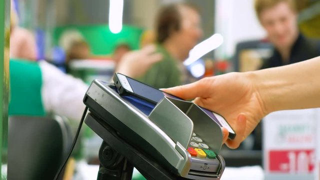 person pays using smartphone and terminal in supermarket