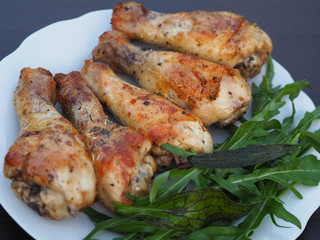 Delicious and roasted leg of chicken with a Golden crust and arugula greens on a white plate for a picnic.
