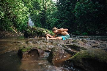 Yoga practice and meditation in nature. Man practicing near river