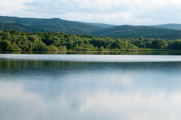 Fototapeta na wymiar beautiful summer lake against the background of high mountains and blue sky