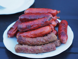 Delicious Hot dogs, sausages, wieners are in a white plate on a dark table. Family picnic  is on Sunday.