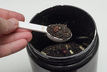 measuring spoon with tea in the hand of man