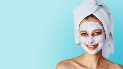 Beautiful young woman with facial mask on her face. Skin care and treatment, spa, natural beauty and cosmetology concept.
