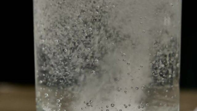 Glass of water with aspirin white tab. Sparkling Bubbles in glass of water.  Effervescent tablet falls on a bottom of a glass