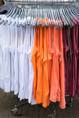 white, orange and red sleeveless tank tops hanging on rack