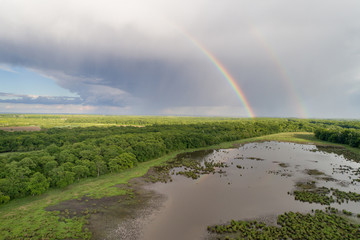 Landscape of plains with two rainbows on sky