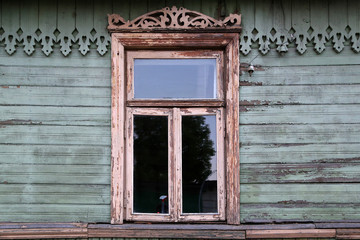 Naklejka na ściany i meble An old wooden window with carved platbands and carved eaves in a village house.