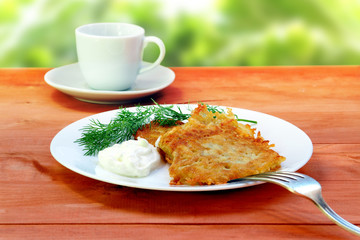 potato pancakes with sour cream on a rustic table