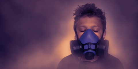 Young boy wearing gasmask, respirator portrait. Effects of worldwide air pollution, industrial influence on environment. Protection from dangerous air particles, gas, smog, transmitted diseases