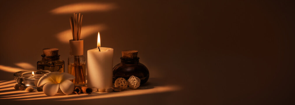 Beautiful spa composition with candles, frangipani flower, oil flasks and other decor elements.