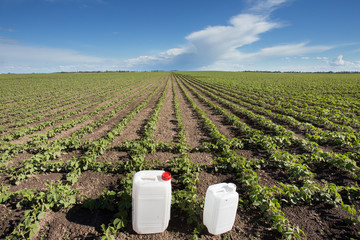 Canisters with pesticides in field - obrazy, fototapety, plakaty
