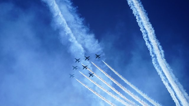airshow in sky by bright sea and traced lines