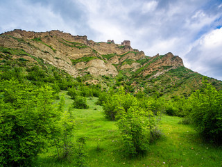 Fototapeta na wymiar Bottom view of a cliff with old Georgian Ksani fortress at its top