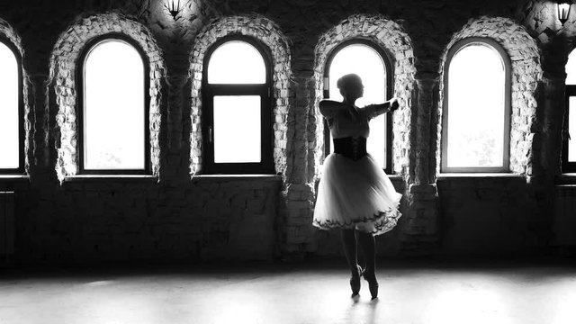 Slow motion young woman dancing modern ballet. Ballet woman practicing ballet position in dance studio. Monochrome style.