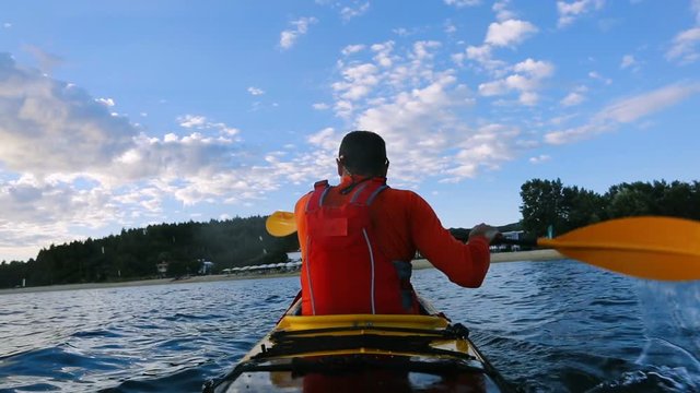 Rear view of kayaker paddling touring kayak on the sea