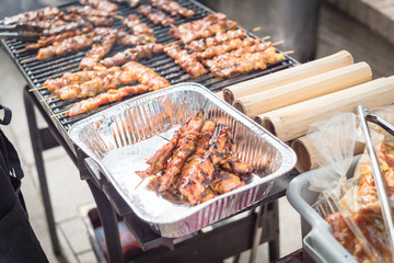 Tasty pork BBQ skewers in aluminum foil tray at local market in America