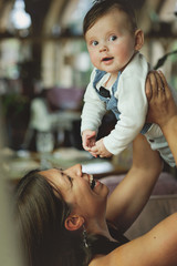 Mother lifting and playing with baby boy