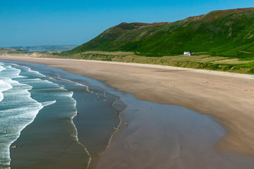 A huge golden sandy beach with breaking surf and green hills