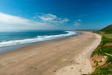 Fototapeta na wymiar Surf and waves breaking on the beautiful golden sandy beach of Rhossili on the Gower Peninsula, Wales