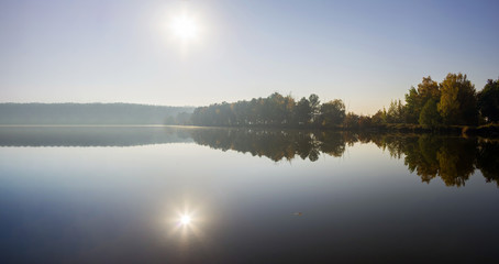 Panorama with bright sun reflected in the water of the lake. Calm on the lake.
