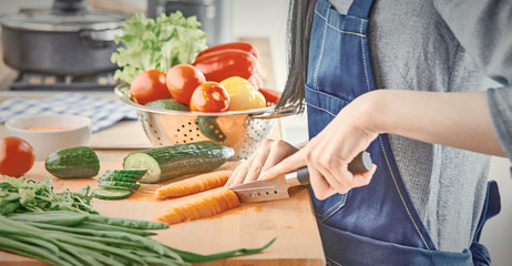 A young woman prepares food in the kitchen. Healthy food - vege