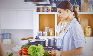A young woman prepares food in the kitchen. Healthy food - vege
