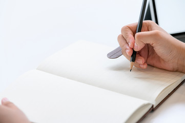 Closeup of woman's hand use pencil writing on notebook.