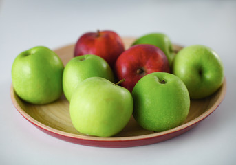Green and red apple lies on a white table