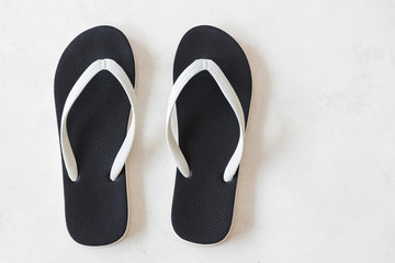 Black beach sandals on white floor with copy space. Overhead shot