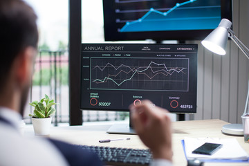 Fototapeta premium Diagrams displayed on computer monitor analysed by young businessman