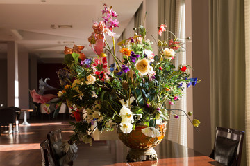 A bouquet of flowers in the hotel lobby. Arrangement of artificial flowers in a clay pot on a table in a hotel.